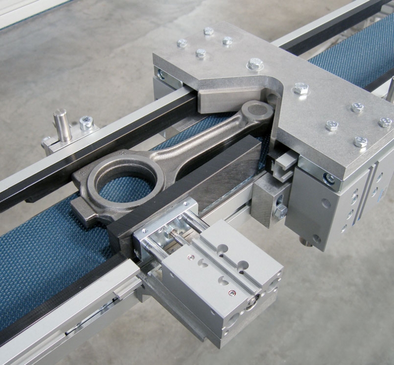 Flat belt conveyor with product nest and pneumatic stop